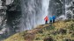 Three hikers enjoying the view of a large water fall in Chile.